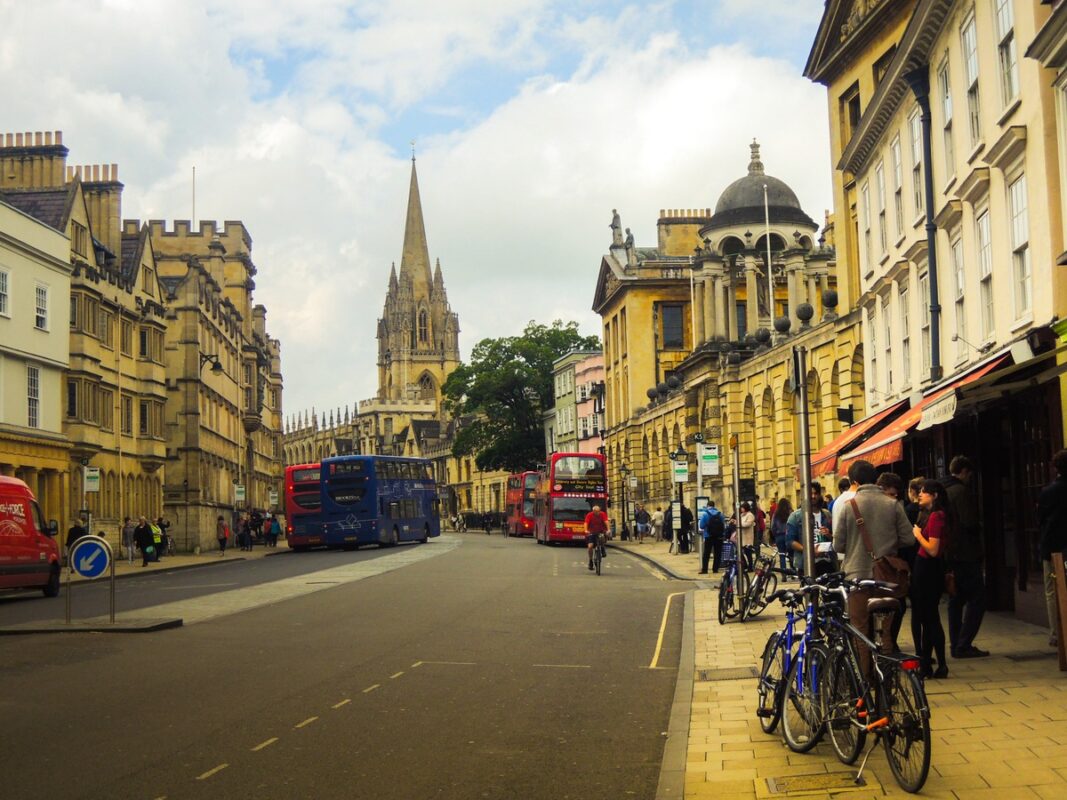 Oxford combina historia, arquitectura y ambiente cultural Calle principal de Oxford con autobuses rojos, bicicletas y edificios históricos durante una excursión desde Londres.