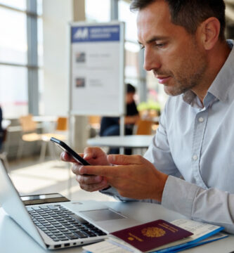 Viajero comparando seguros de viaje en el aeropuerto con portátil, móvil y pasaporte