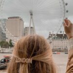 Una mujer con un gancho del pelo que dice London simula "sujetar" con las manos el London Eye