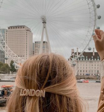 Una mujer con un gancho del pelo que dice London simula "sujetar" con las manos el London Eye