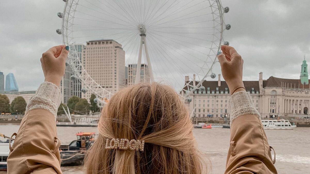 Una mujer con un gancho del pelo que dice London simula "sujetar" con las manos el London Eye