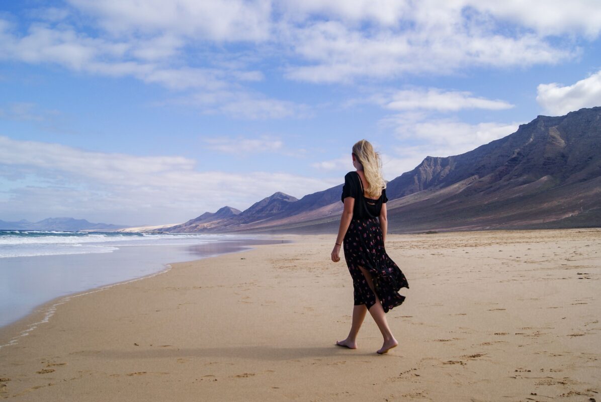 Dónde se rodó Han Solo en Fuerteventura: localizaciones y cómo visitarlas 1 Mujer caminando por la playa de Cofete con las montañas de Jandía al fondo, en Fuerteventura