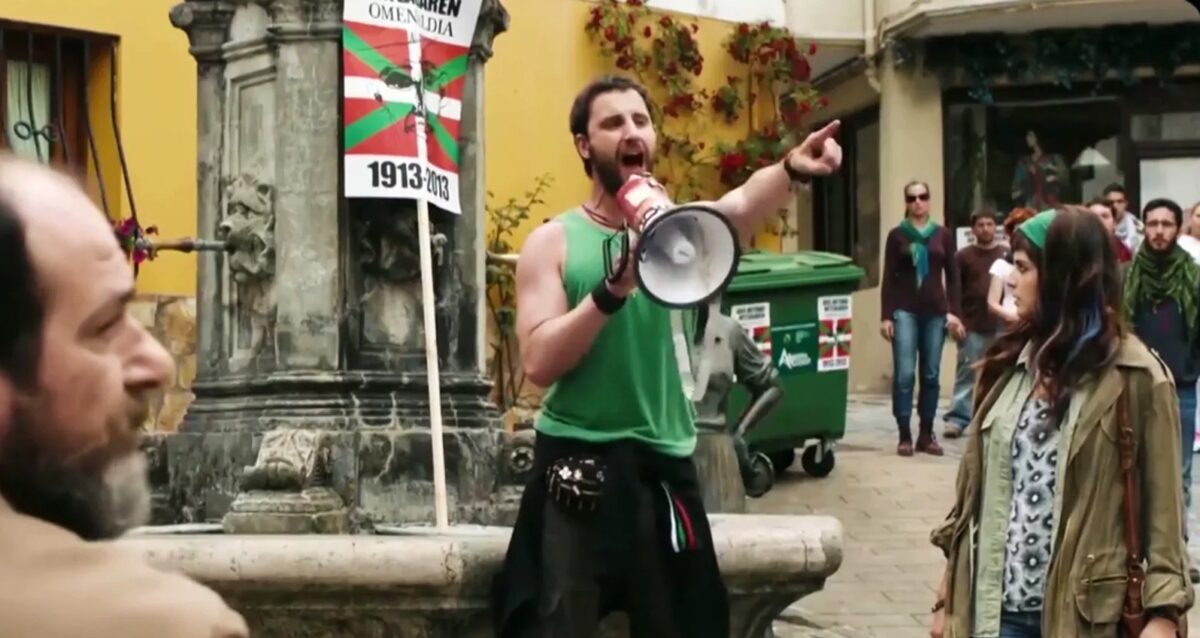 Ruta por los escenarios de Ocho apellidos vascos 1 Escena de Ocho apellidos vascos en una plaza de Zumaia con una persona hablando por megáfono
