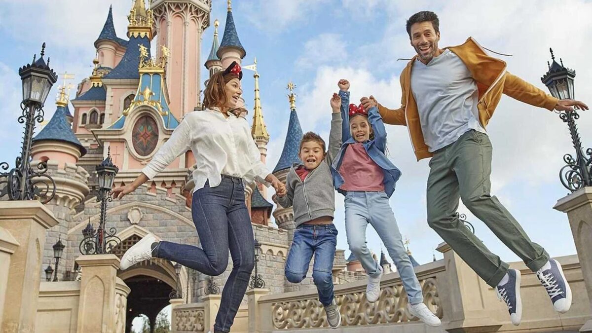 Una pareja con niños salta de alegría frente al castillo de la Bella Durmiente de Disneyland París