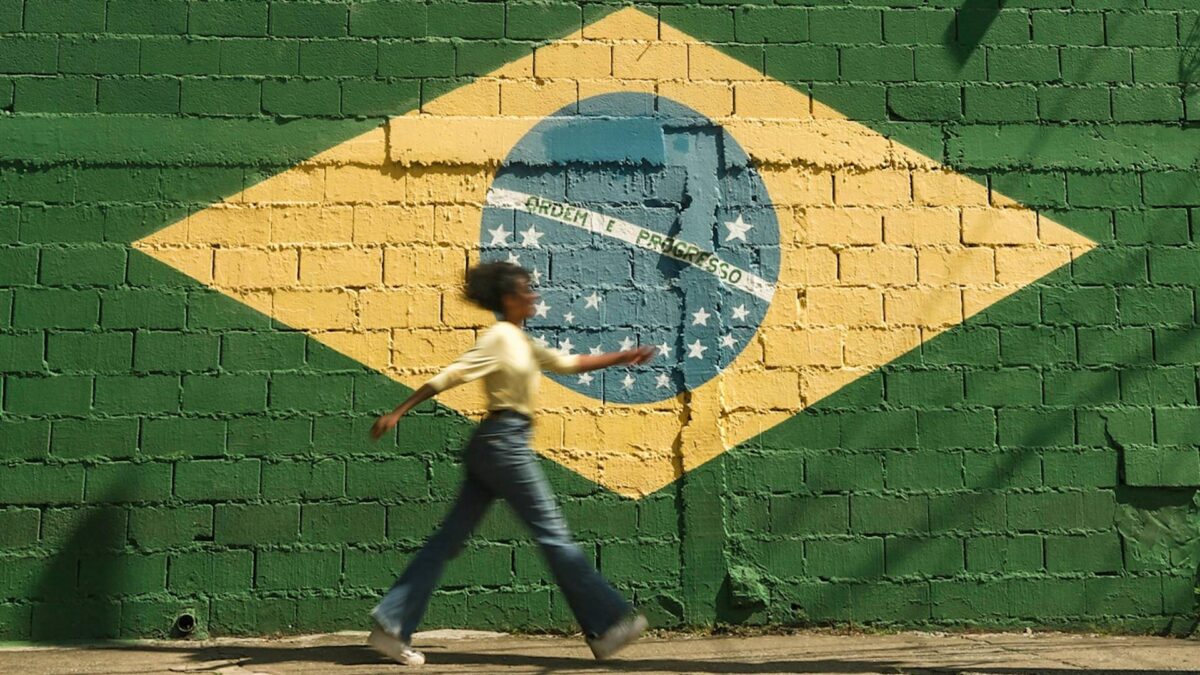 Una mujer pasa por delante de una pared pintada con la bandera de Brasil