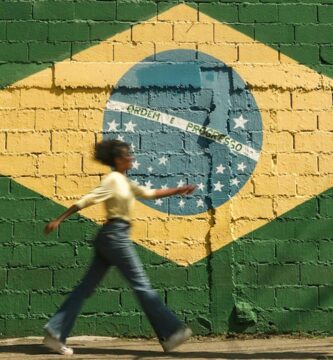 Una mujer pasa por delante de una pared pintada con la bandera de Brasil