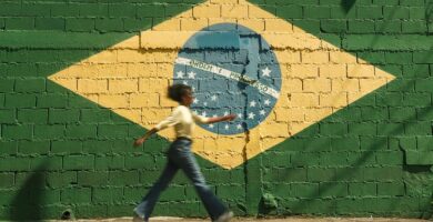 Una mujer pasa por delante de una pared pintada con la bandera de Brasil