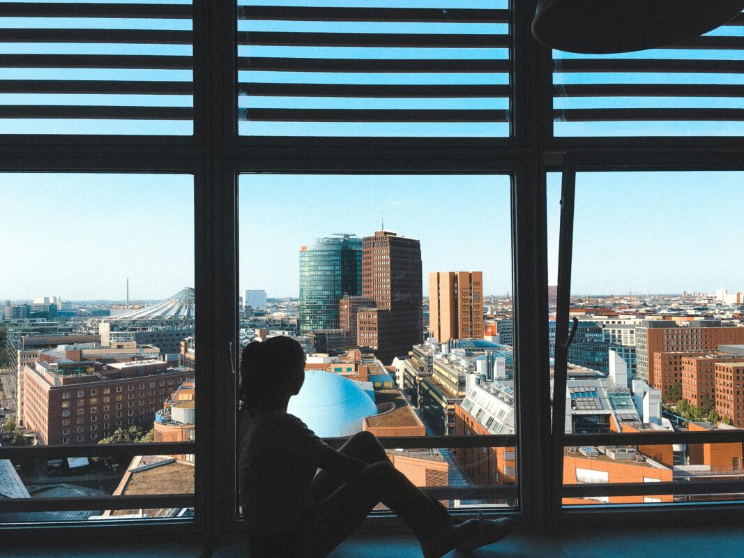 Persona sentada frente a una ventana con vistas panorámicas de Berlín