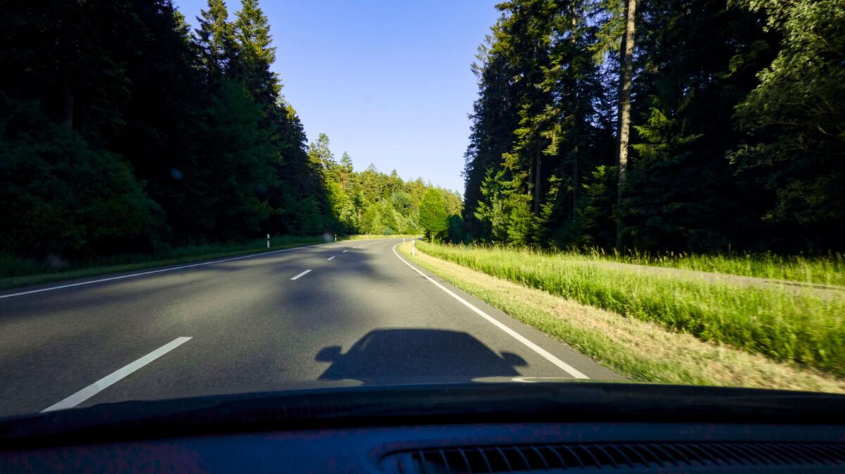 Alquilar coche en Alemania: cuándo lo necesitas y qué mirar antes de pagar 1 Coche circulando por una carretera arbolada en Alemania