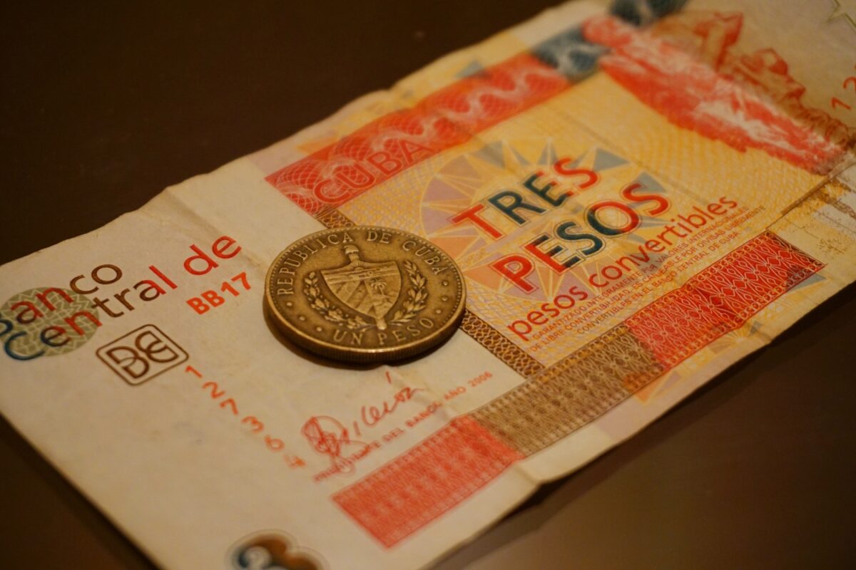 Antiguo billete cubano de tres pesos convertibles junto a una moneda de un peso