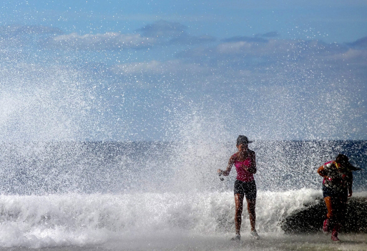 Personas junto al fuerte oleaje en la costa de Cuba