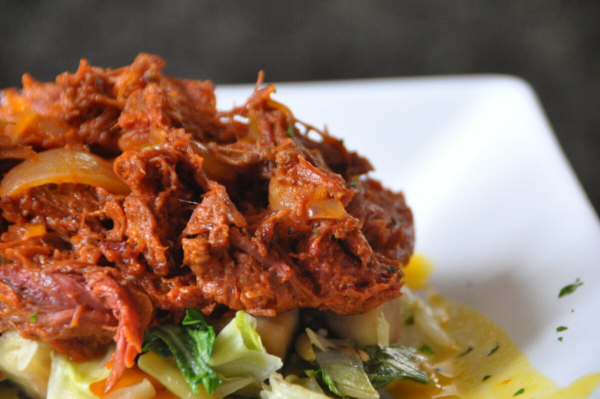 Plato de ropa vieja cubana con carne deshilachada, verduras y salsa
