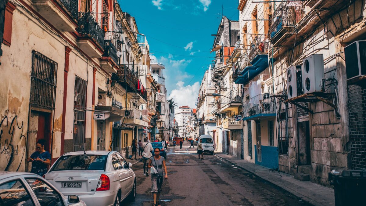 Calle de Centro Habana con vecinos, coches y edificios de fachadas envejecidas