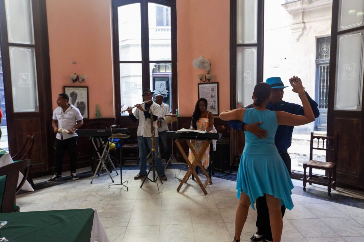 Pareja bailando salsa mientras un grupo de músicos actúa en directo en La Habana