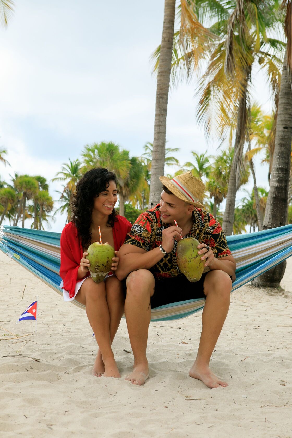 Pareja disfrutando de una playa cubana Pareja sentada en una hamaca con cocos en una playa tropical