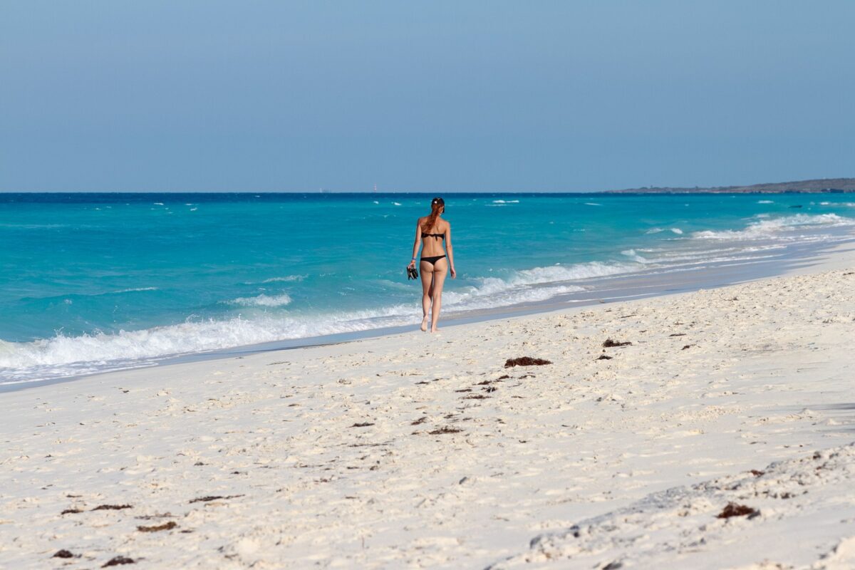 Mujer caminando por una playa de arena blanca y aguas turquesas en Varadero